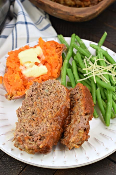Two slices of meatloaf with sweet potato and green beans.