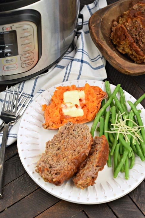 Meatloaf served on a plate with sweet potato and green beans.