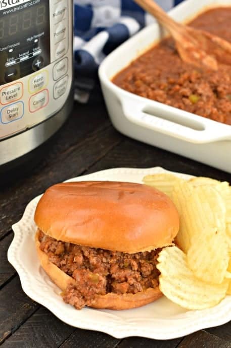 Hamburger bun with sloppy joes and wavy potato chips.