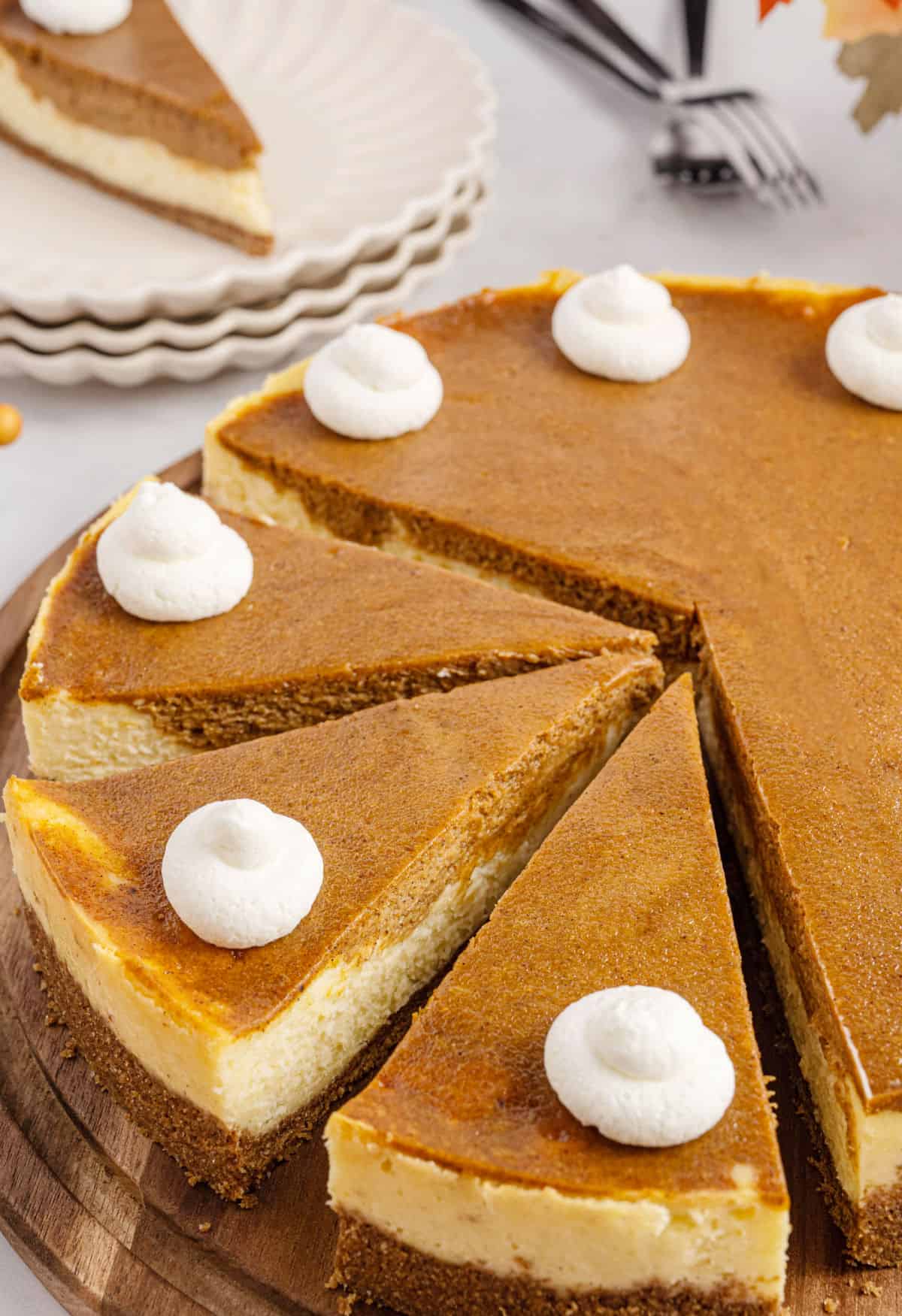 Whole pumpkin cheesecake cut into slices topped with whipped cream.
