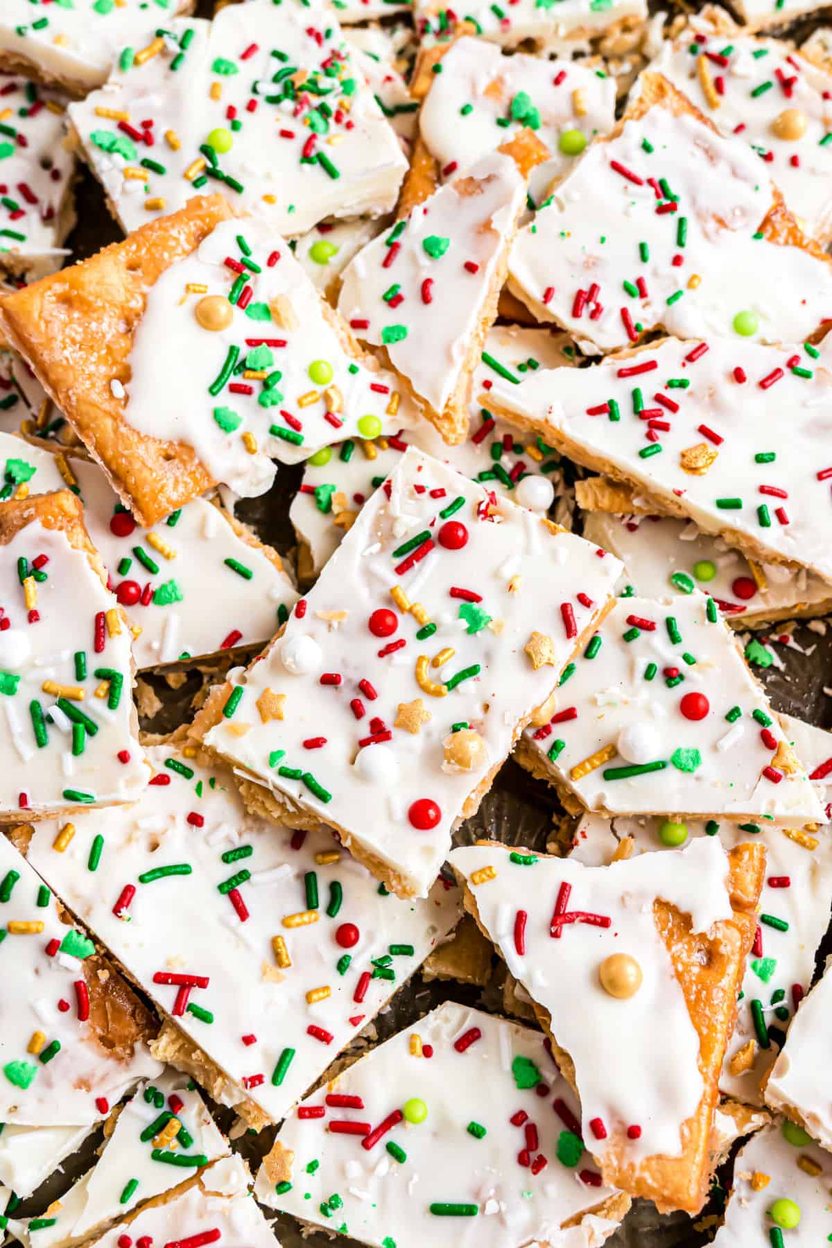 Brocken pieces of Christmas crack stacked on a cookie sheet.
