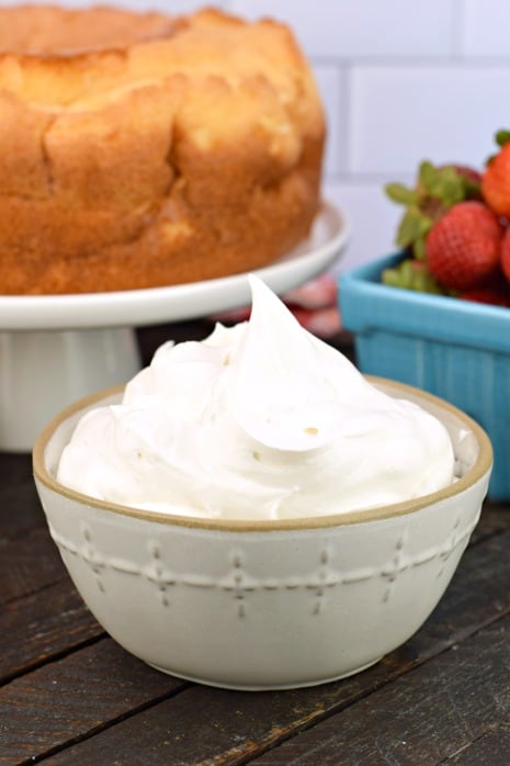 Whipped Cream in a bowl with an Angel Food cake in the background.
