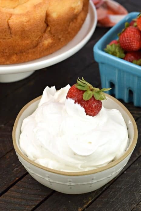 Homemade whipped cream in a bowl with fresh strawberries