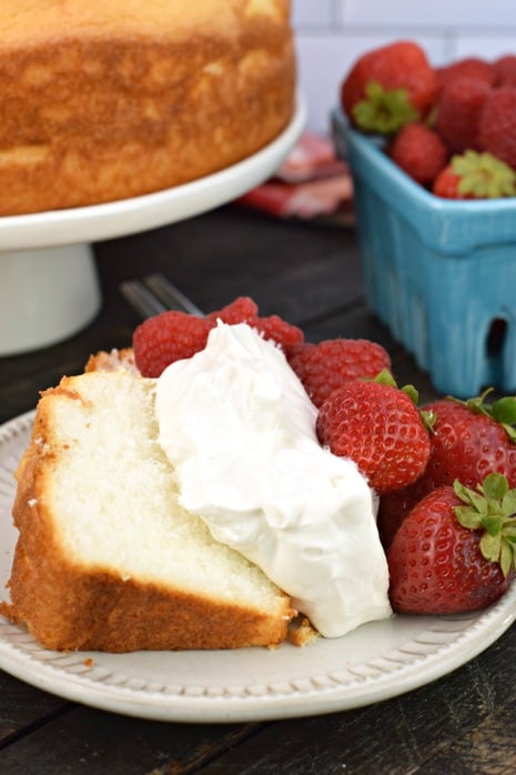 Slice of angel food cake with fresh whipped cream and strawberries.