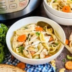 Bowl of comforting chicken noodle soup with carrots and parsley, a spoon, and an Instant Pot in the background.
