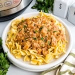 Creamy chicken stroganoff served over egg noodles on a white plate, garnished with parsley—an easy twist inspired by Instant Pot chicken paprikash.