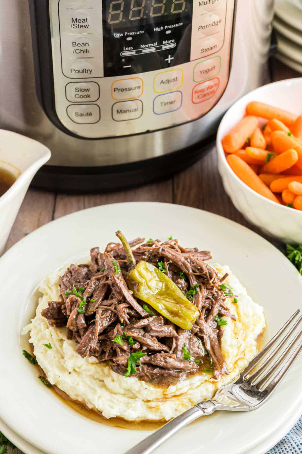 Mississippi pot roast served on a plate of mashed potatoes.