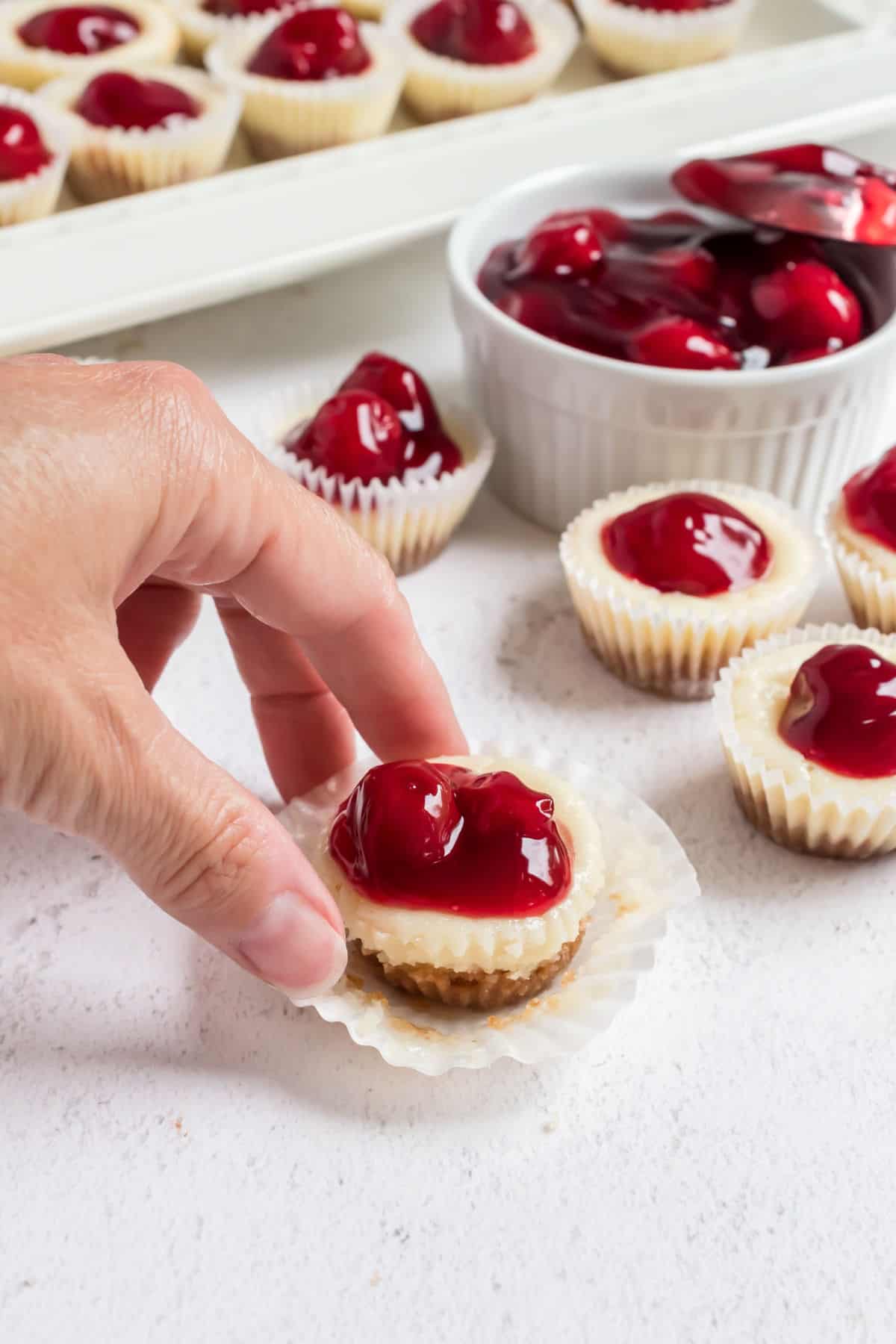 Mini cherry cheesecake unwrapped and being picked up.
