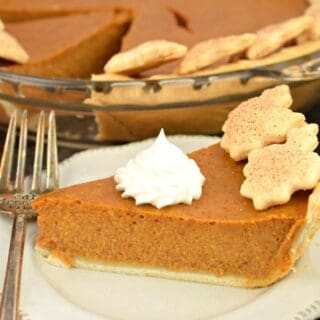 Slice of pumpkin pie with dollop of whipped cream on top.