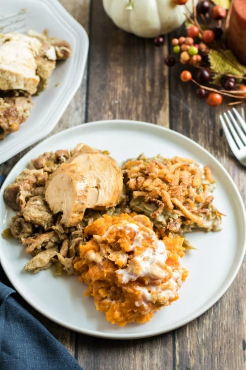 Dinner plate with sweet potato casserole, green bean casserole, turkey and stuffing.