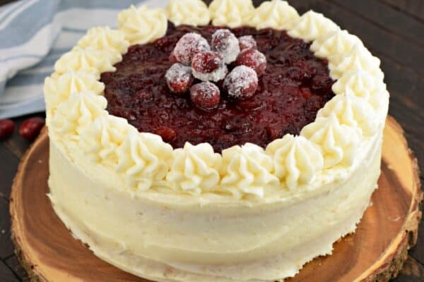 White layer cake with almond buttercream frosting. Topped with cranberry filling and fresh sugared cranberries.
