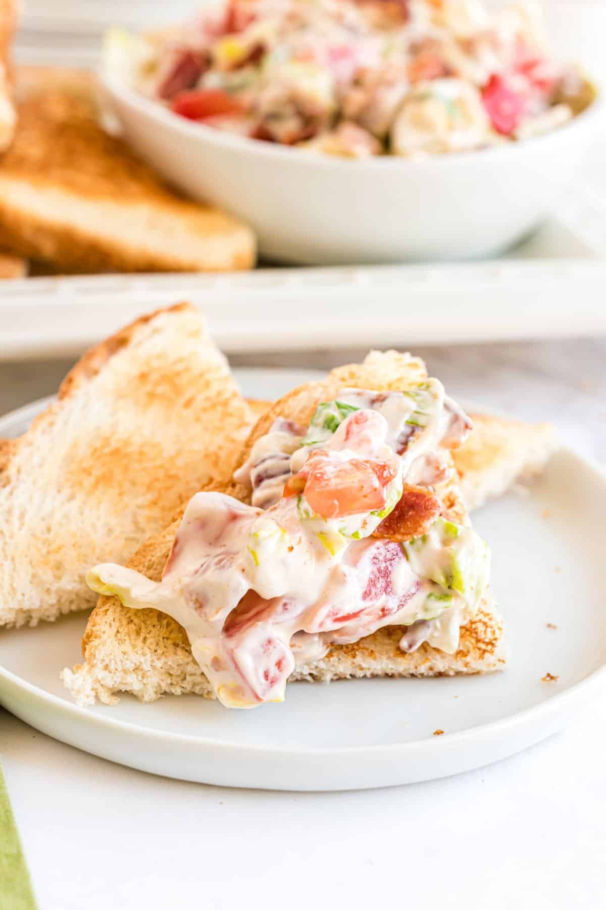 Blt dip served on toast triangles on a white plate.