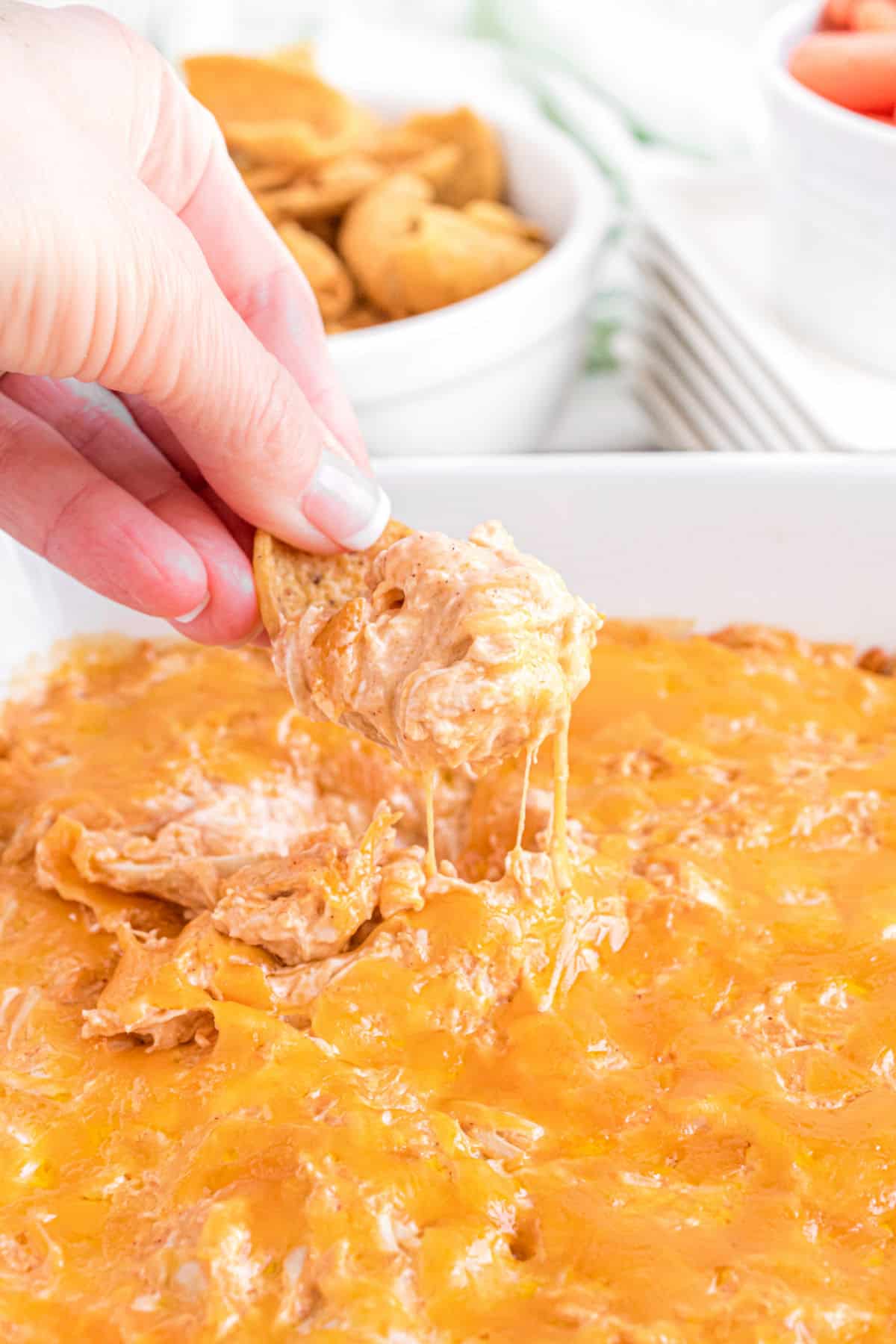 Buffalo chicken dip being scooped with a frito corn chip.