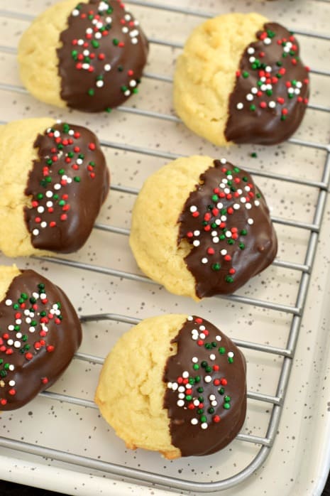 Butter Cookies dipped in dark chocolate with holiday sprinkles on a wire cooling rack
