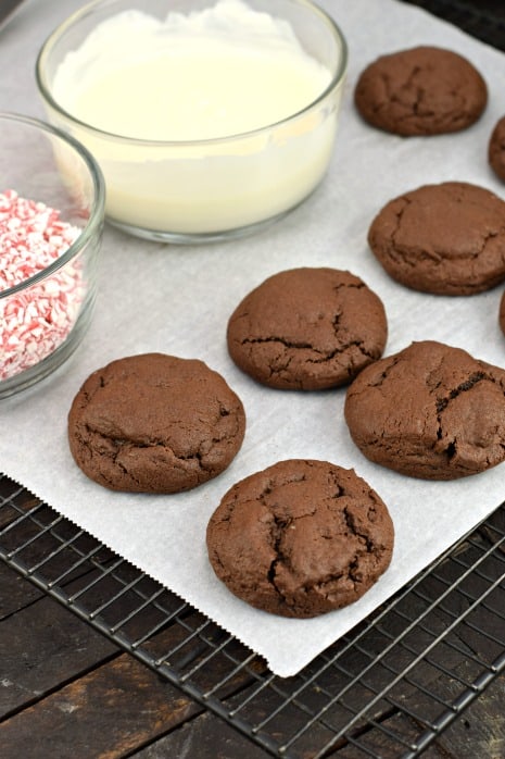 Chocolate cookies on parchment paper ready to dip in melted white chocolate.