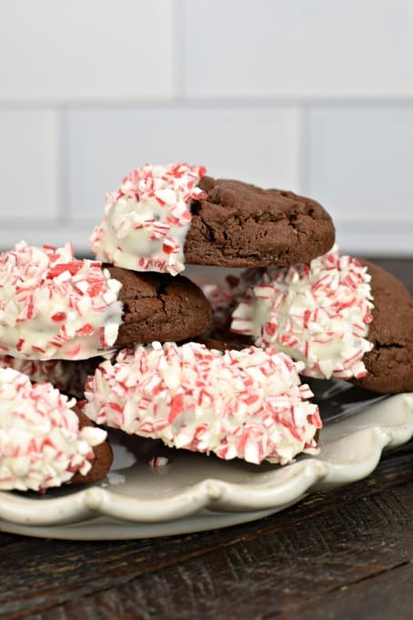Stack of chocolate cookies on a plate, dipped in white chocolate and candy canes.