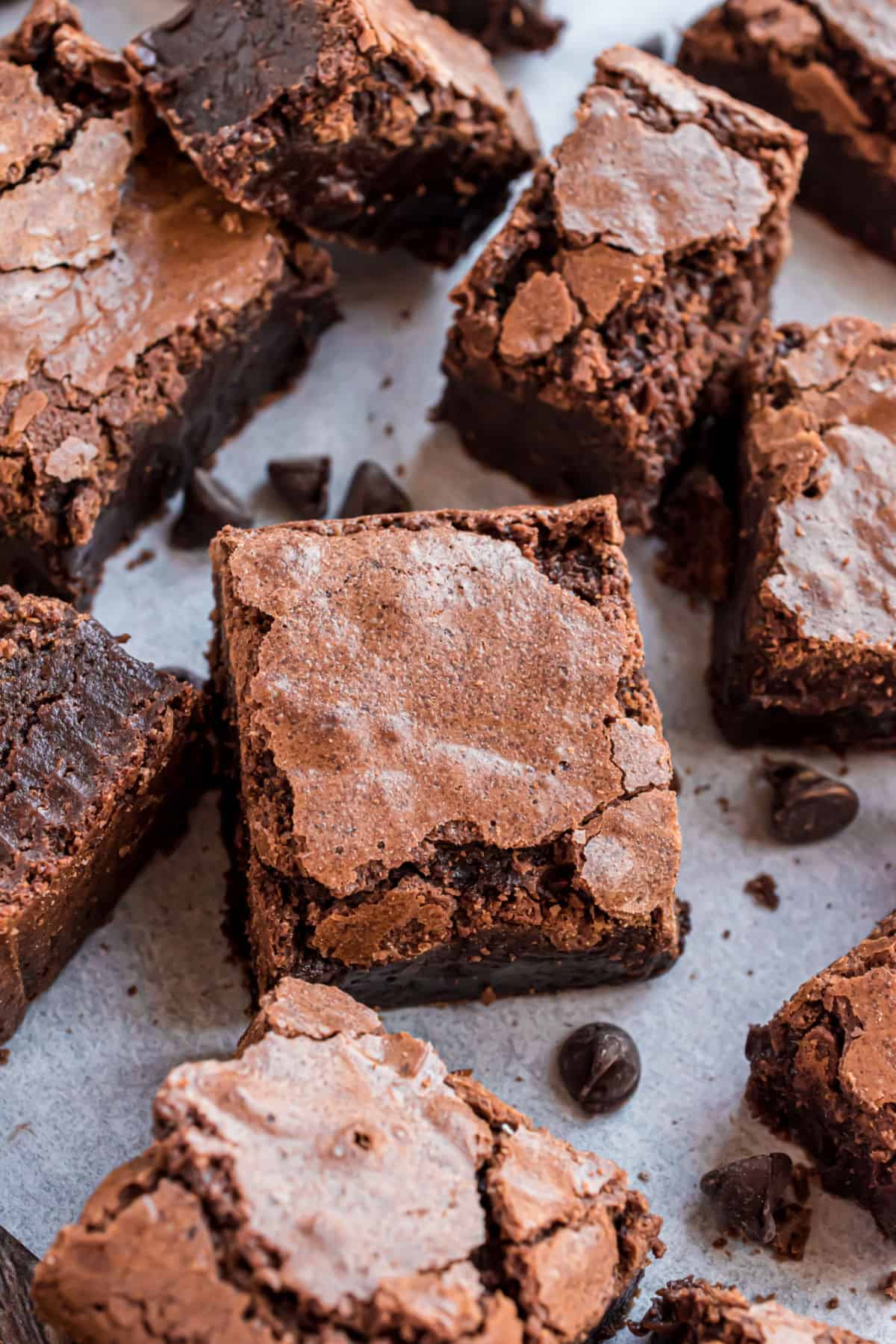 Small squares of fudgy homemade brownies on a piece of parchment paper.