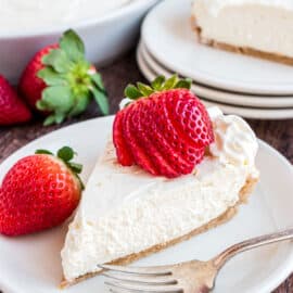 Slice of cheesecake with fresh strawberry and whipped cream.