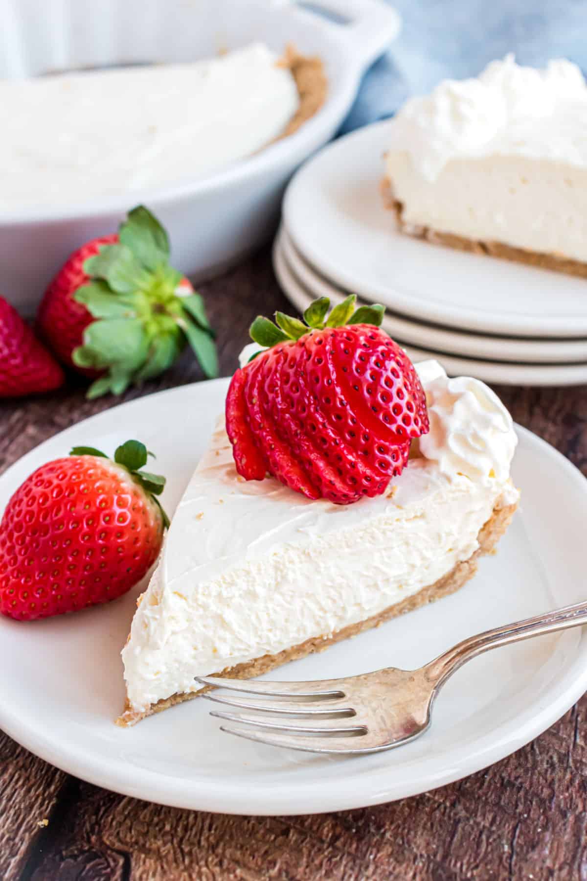 Slice of cheesecake with fresh strawberry and whipped cream.