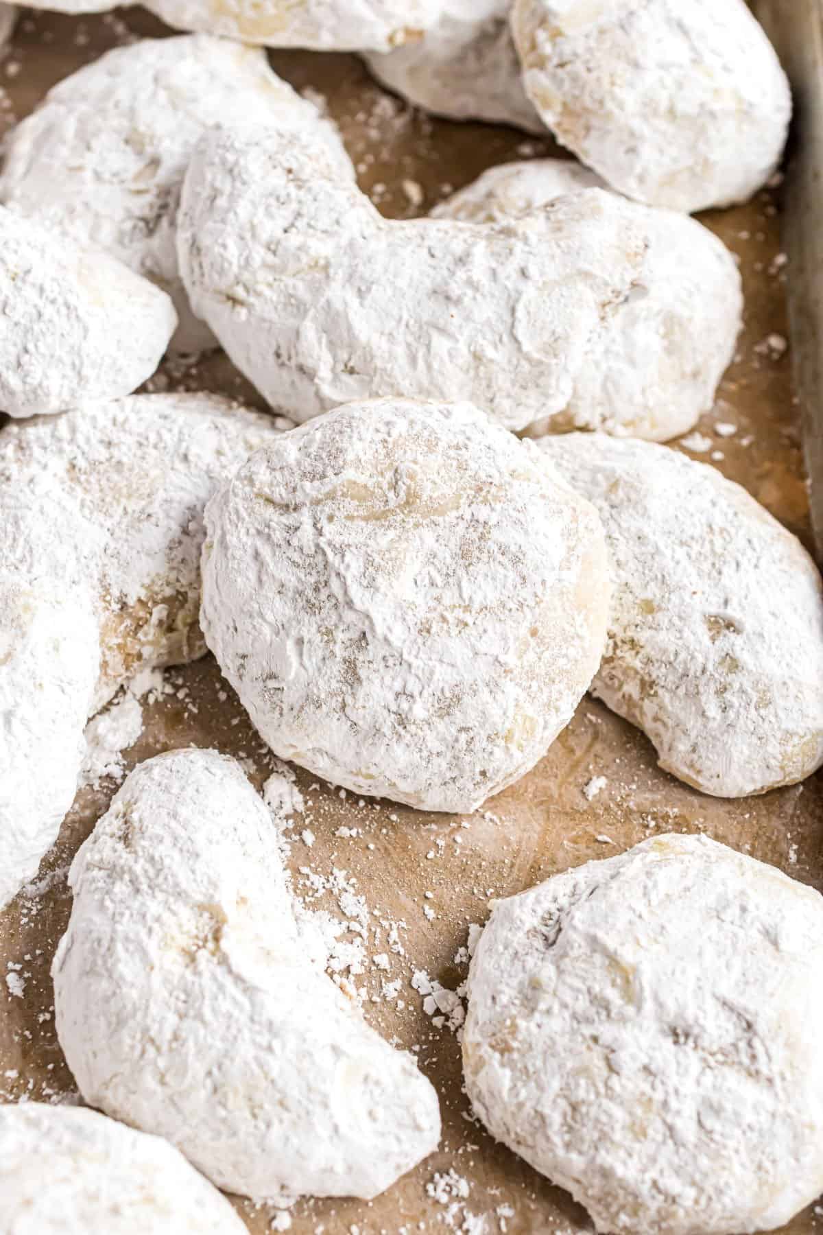Snowball cookies on parchment paper with powdered sugar.