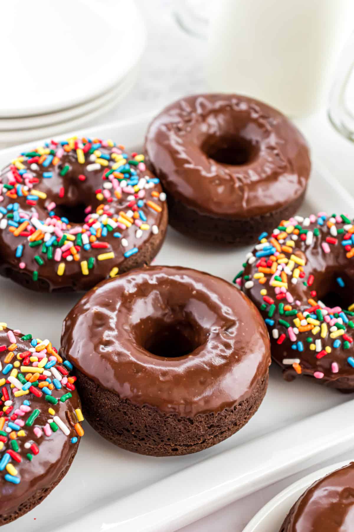 Chocolate glazed donuts on a white plate.