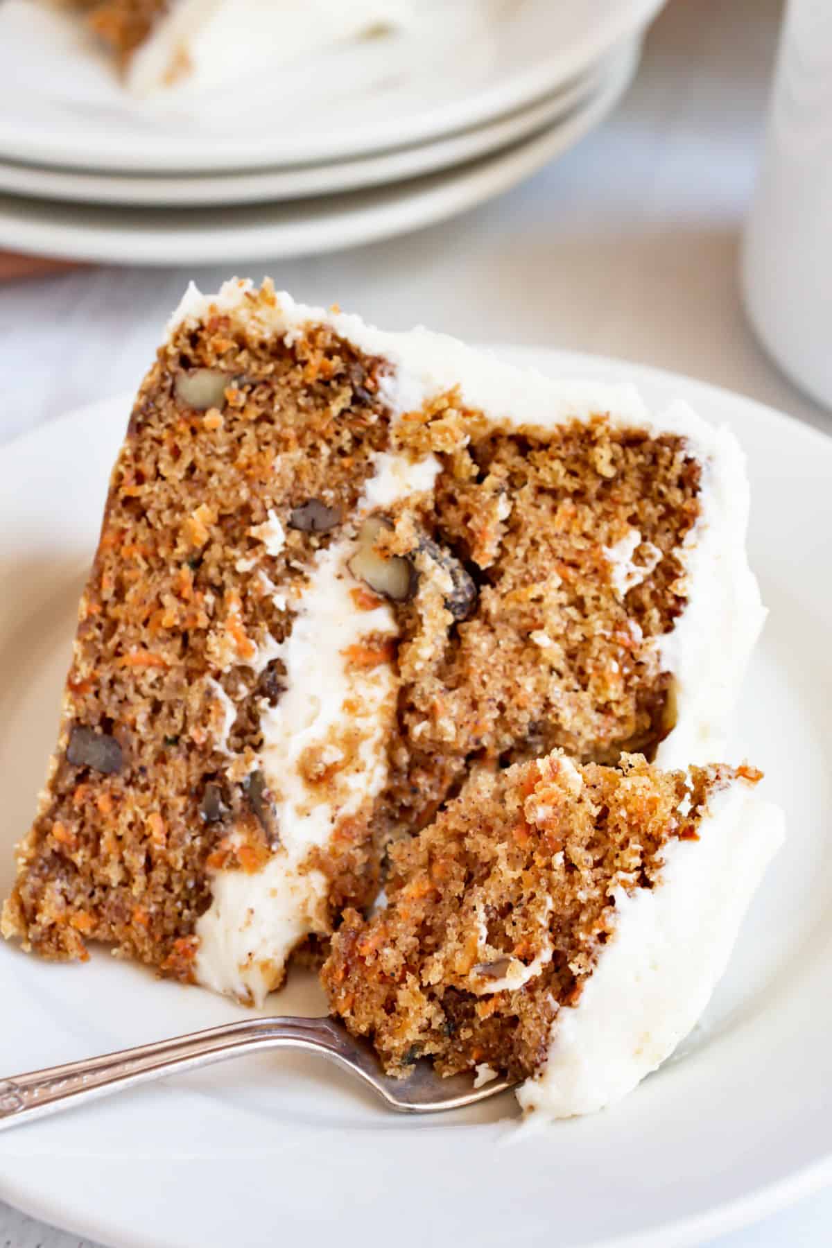 Slice of carrot layer cake on a plate with a fork.