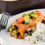 Chicken enchilada with avocado served on plate with cilantro lime rice.