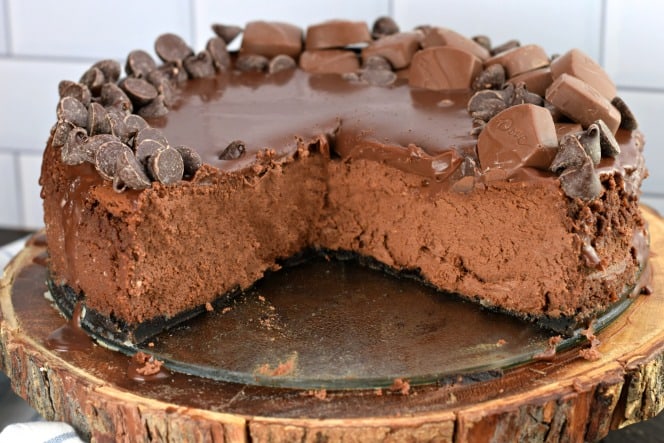 Chocolate cheesecake with large piece removed and creamy filling exposed.