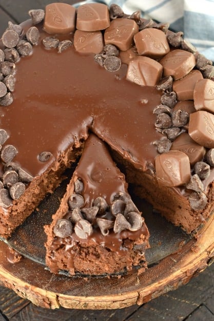 Whole chocolate cheesecake with one slice cut.