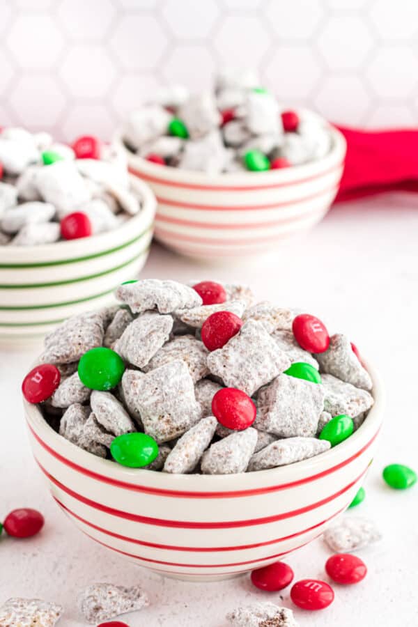 Christmas puppy chow in a white and red striped bowl.