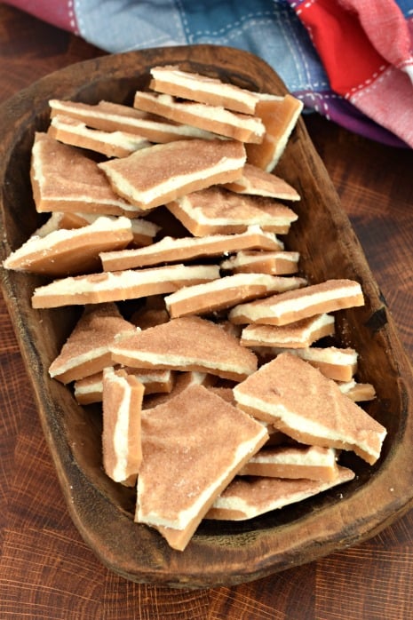 Wooden oval shaped bowl filled with pieces of churro flavored toffee.