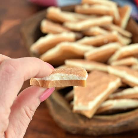 Piece of white chocolate topped toffee being held up to see the two layers.