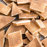 Cinnamon sugar churro toffee pieces with rich white chocolate layers are stacked unevenly.