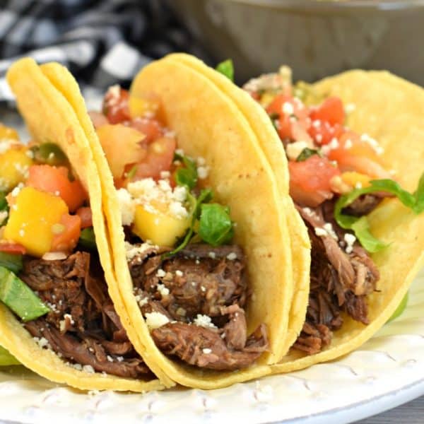 Corn tortillas filled with barbacoa beef, pico de gallo, cotija cheese, and lettuce.