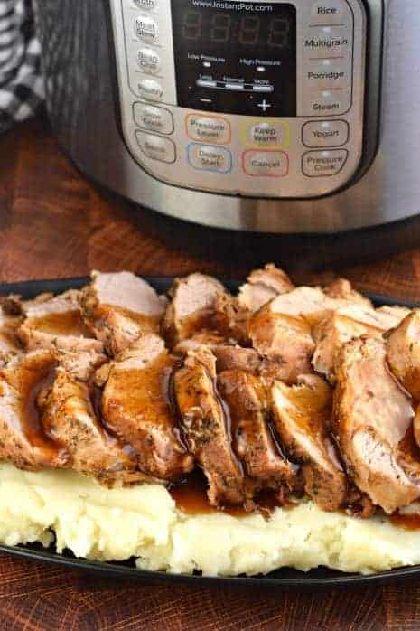 Sliced Pork Tenderloin covered in balsamic glaze and served over a plate of mashed potatoes.