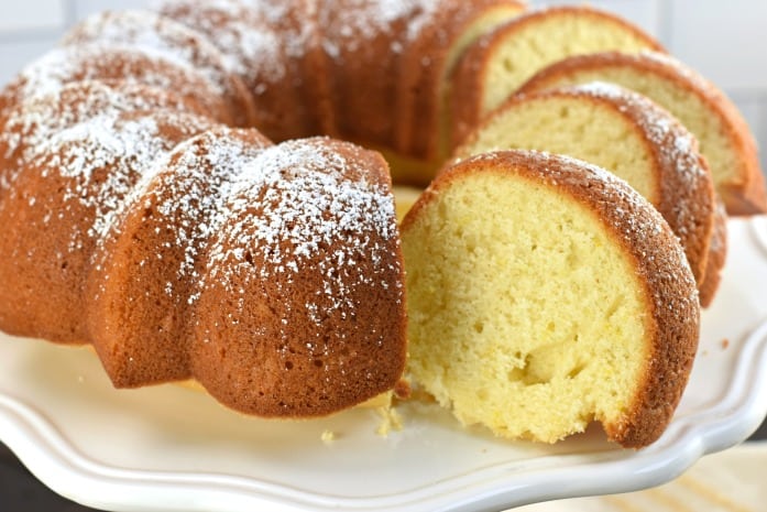 Italian Cream Cake with Lemon and powdered sugar on top. Sliced on a white cake plate.