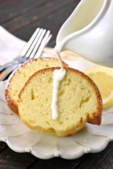 Two slices of Italian Lemon Cake with a pitcher of fresh cream drizzled over the top of the cake.
