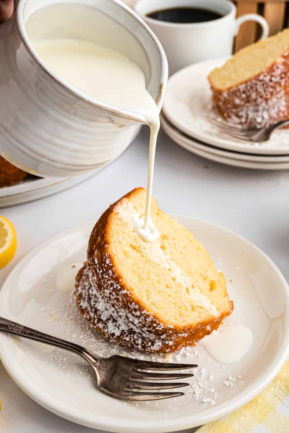 Cream being poured over a slice of lemon cake.