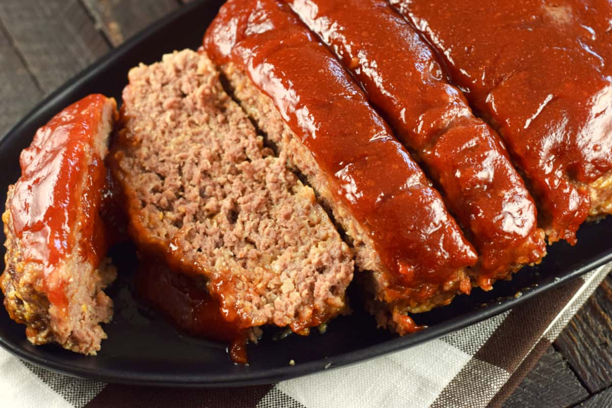 Sliced meatloaf with glaze on a serving plate.