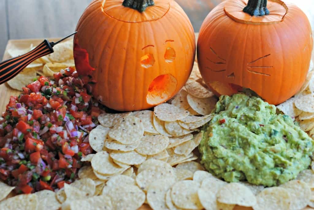 Two pumpkins carved and served with guacamole and pico de gallo.