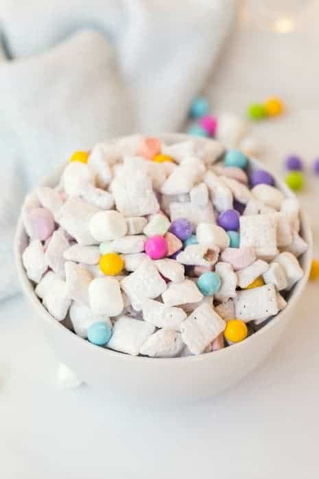 Puppy chow with pastel sixlets in a white bowl.
