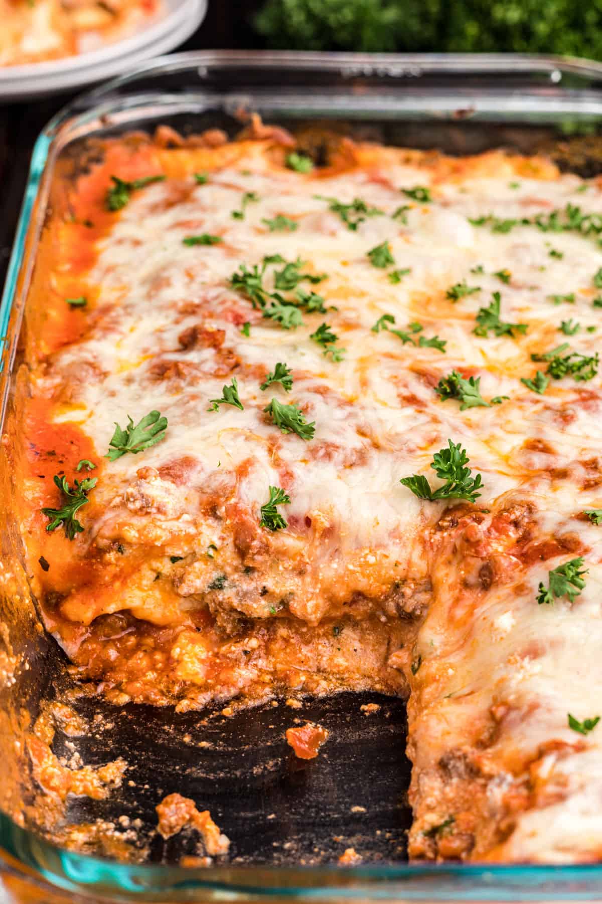 Ravioli lasagna in clear glass 13x9 baking dish with one scoop removed.