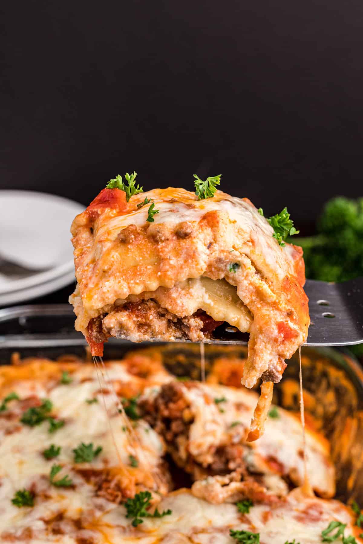 Ravioli lasagna being scooped out of baking dish.