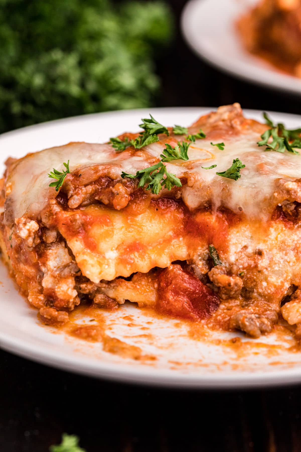 Ravioli lasagna served on a white dinner plate with fresh parsley.