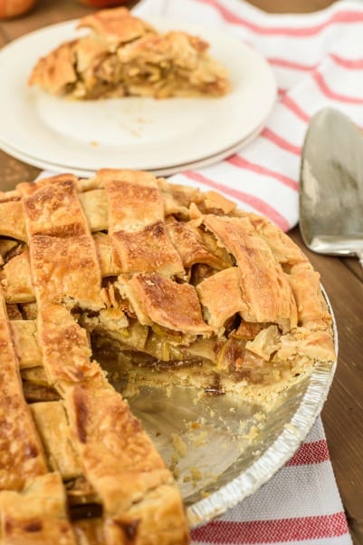 Apple PIe with flaky crust and one slice on a white plate.