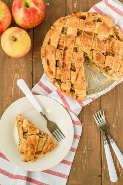 Apple Pie with lattice top. One slice served on a white plate with white fork.