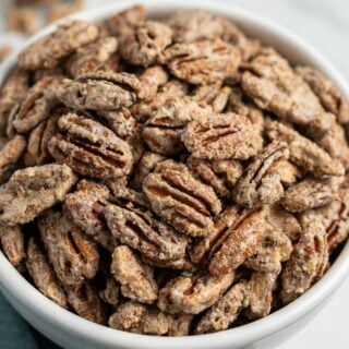 Candied pecan halves in a white bowl.