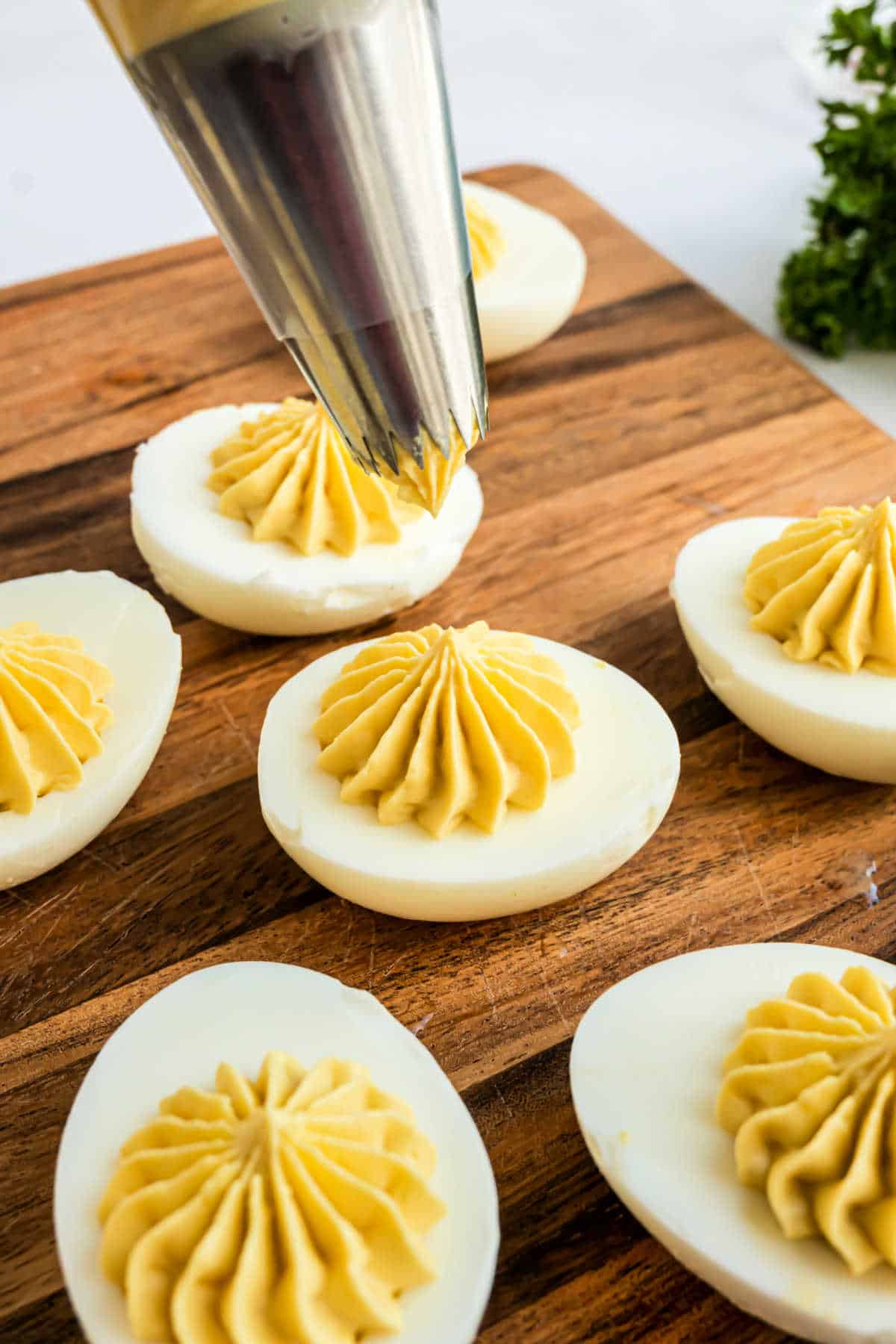 Deviled egg filling being piped onto an egg white.