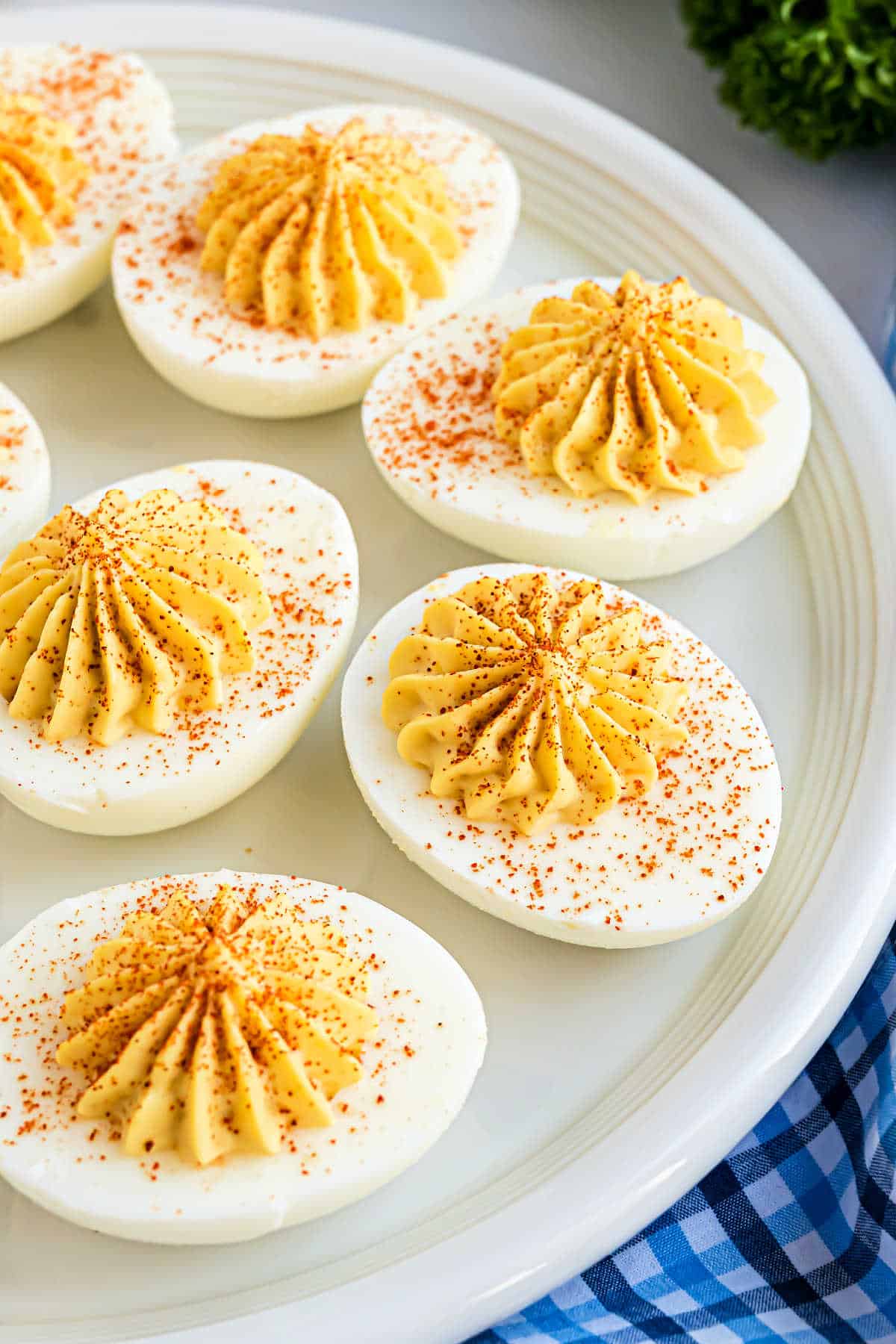 Deviled eggs with paprika on a white serving plate.