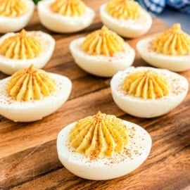 Deviled eggs on a wooden cutting board.